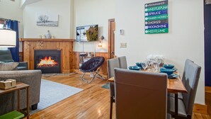 Una sala de estar acogedora con chimenea, un comedor con vajilla azul y un letrero en la pared que enumera varias marcas.