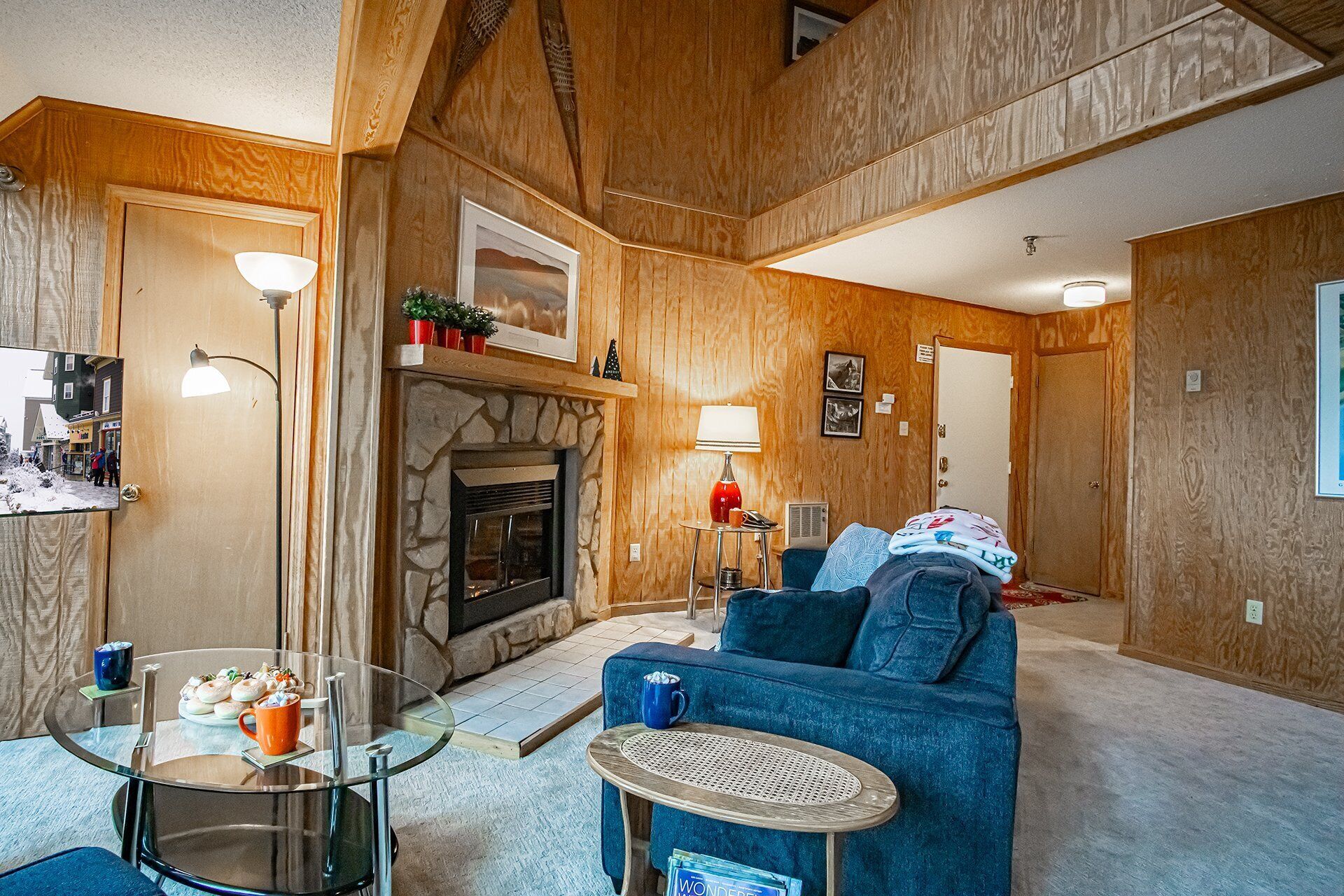 Ein gemütliches Wohnzimmer mit Kamin, einem blauen Sofa, einem Glastisch und einem Essbereich mit Tisch und Stühlen.