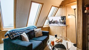 A cozy room with a blue sofa, a small round table with a drink and pastries, and a framed photo on the wall. - Leatherbark - 301b, 2 Bedroom Allegheny Sunrise Spacious Condo Foosball (Snowshoe)