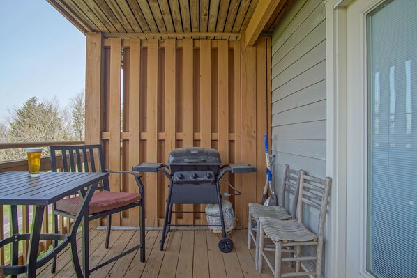 An outdoor patio with a grill, a table with a glass, and two chairs. - Summit 107b 3Br Condo (Snowshoe)