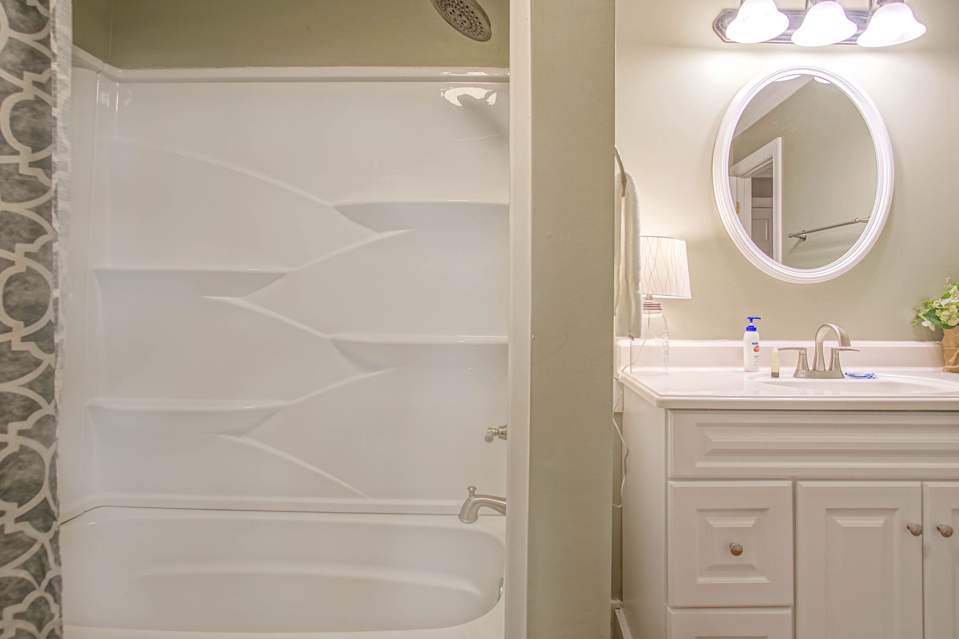 A bathroom with a white bathtub, a sink with a mirror, and a towel rack.