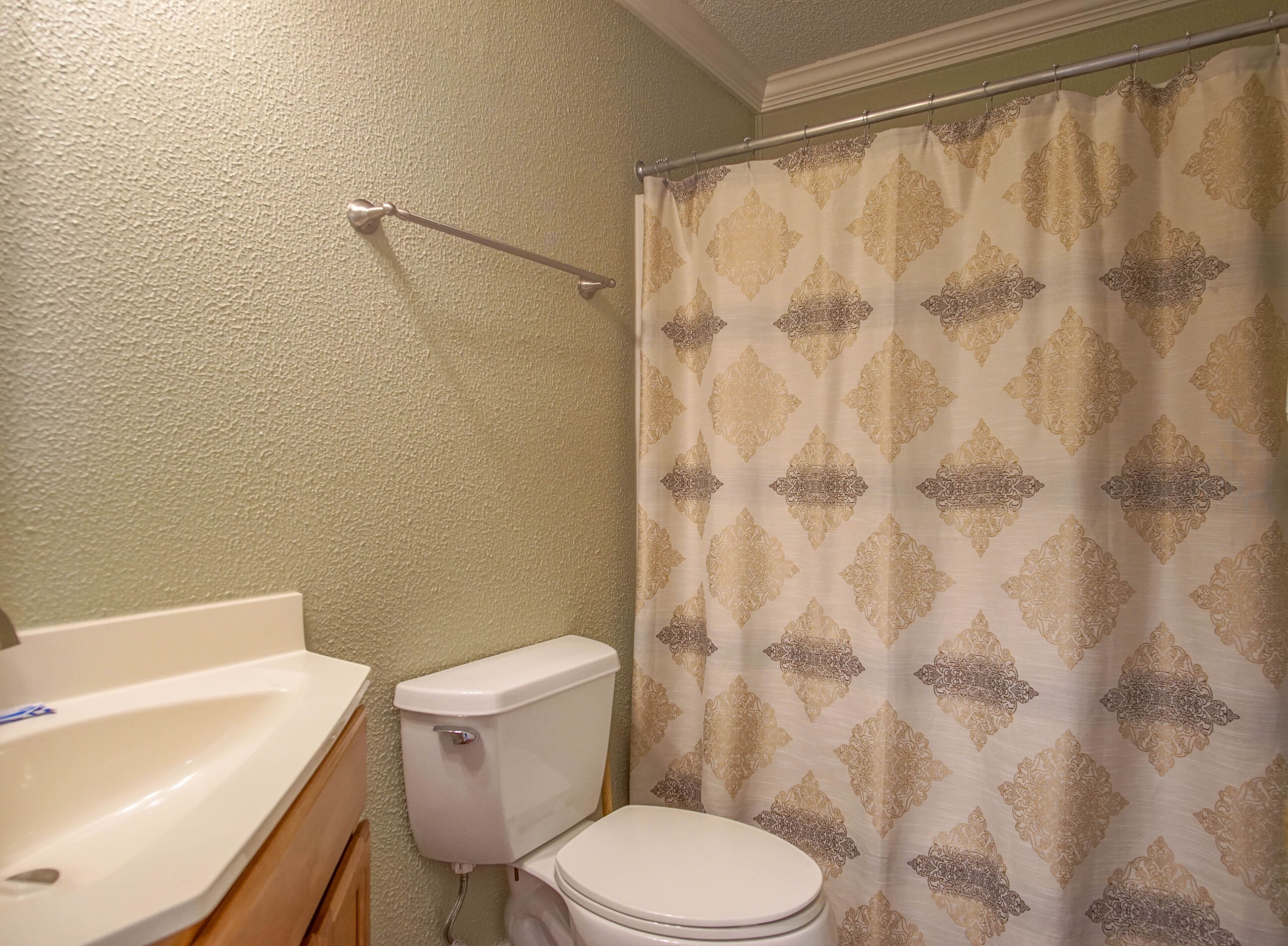 Ein Badezimmer mit Toilette, Waschbecken und einer Duschkabine mit Musterdesign.
