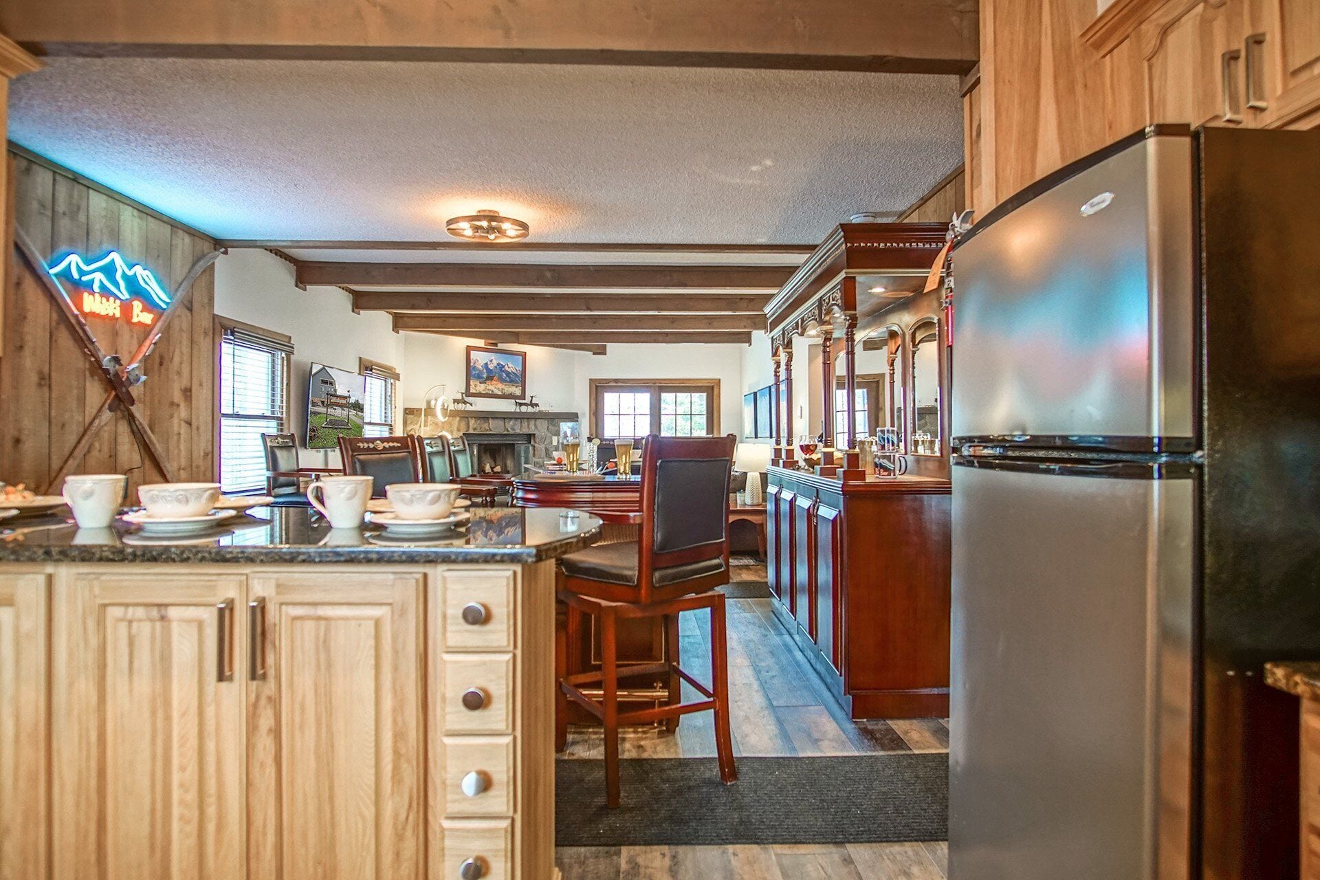 A spacious kitchen with wooden cabinets, a large island, and a stainless steel refrigerator.