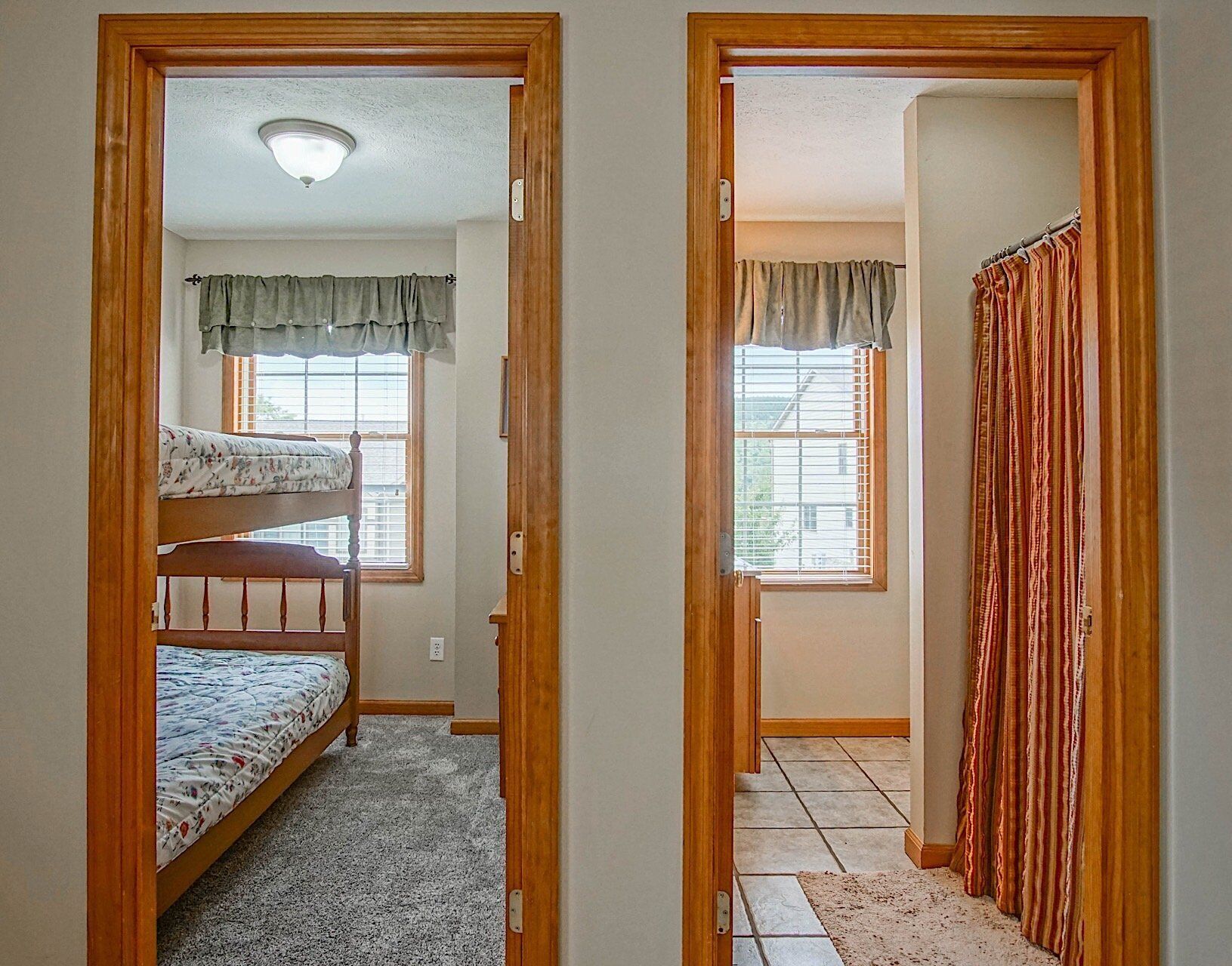A room with two bunk beds and a window with curtains.