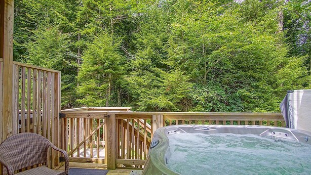 A wooden deck with a hot tub, a wicker chair, and a wooden fence. - Creekside E17, Frisco Kid Retreat Jacuzzi Sleeps 11 (Snowshoe)