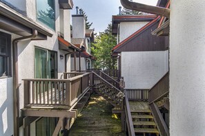 Una estrecha escalera de madera que une dos edificios con paredes blancas y techos oscuros.