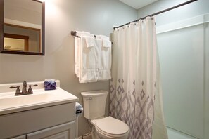 Un baño con lavamanos, inodoro y cortina de ducha.