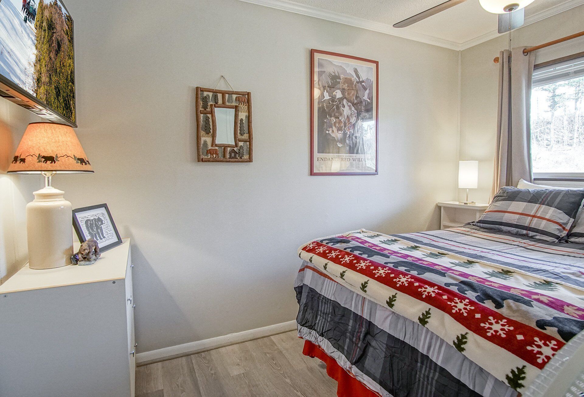 Een slaapkamer met een bed, een nachtkastje, een lamp en twee decoraties aan de muur.