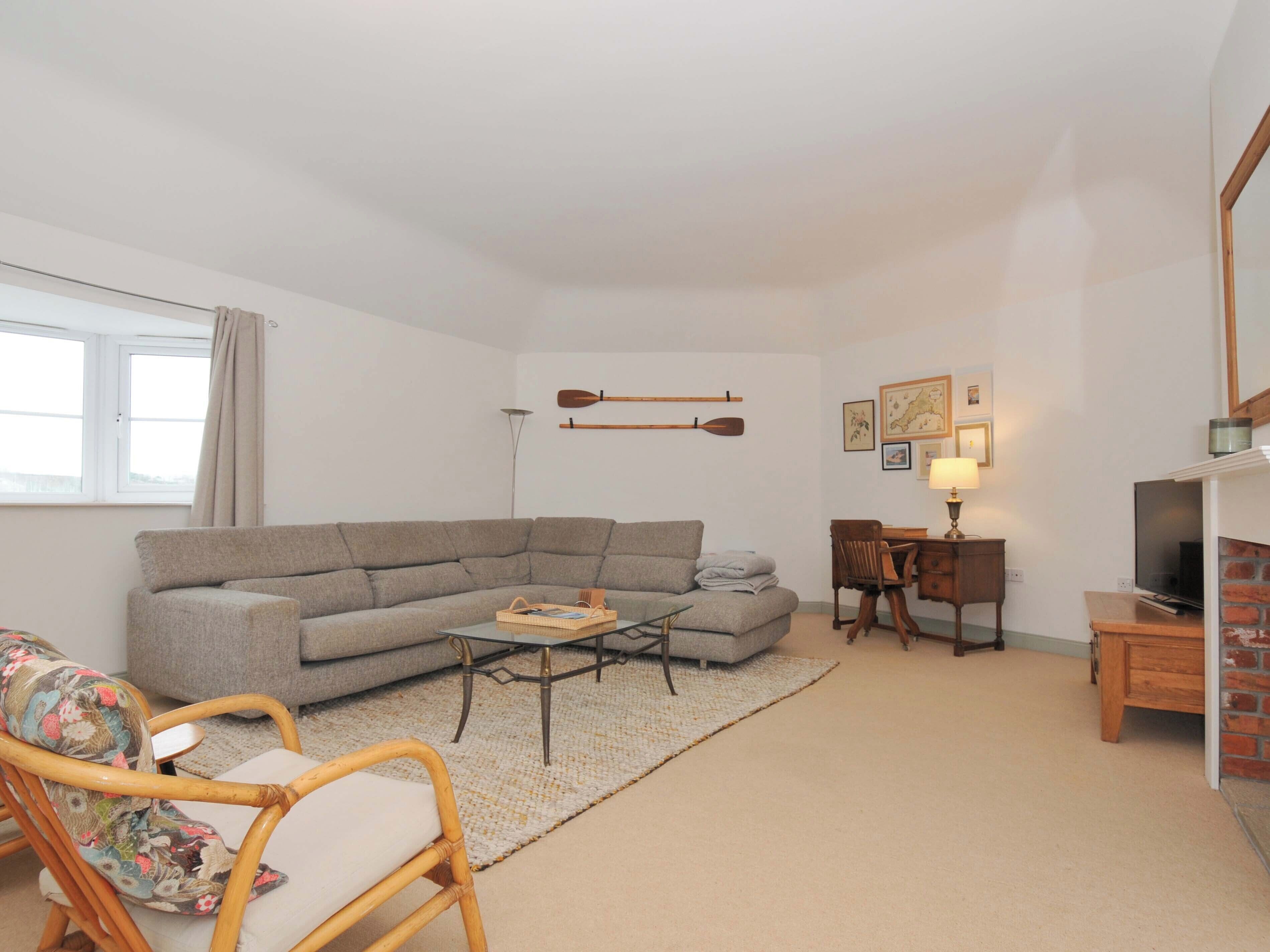 Un salon comprenant un canapé, un fauteuil, une table basse, un téléviseur et une lampe.