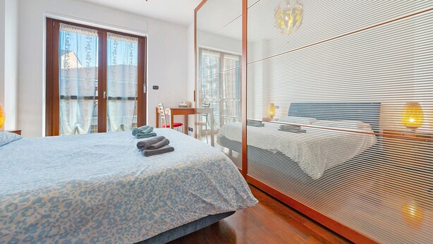 Une chambre à coucher avec un lit, un bureau et un grand miroir.