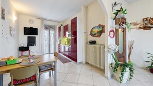 Un espace repas comprenant une table, des chaises, un buffet et une cuisine en arrière-plan.