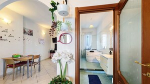 Un espace repas comprenant une table et des chaises, un mur agrémenté d’objets décoratifs et une vue sur la cuisine.