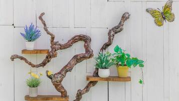 A wall-mounted wooden branch structure with potted plants and a butterfly decoration.