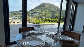 Taula de menjador preparada per a quatre persones amb vista a un paisatge muntanyós a través de grans finestres.