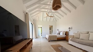 Una habitació àmplia amb un llit gran, un sofà, un televisor i un ventilador de sostre.