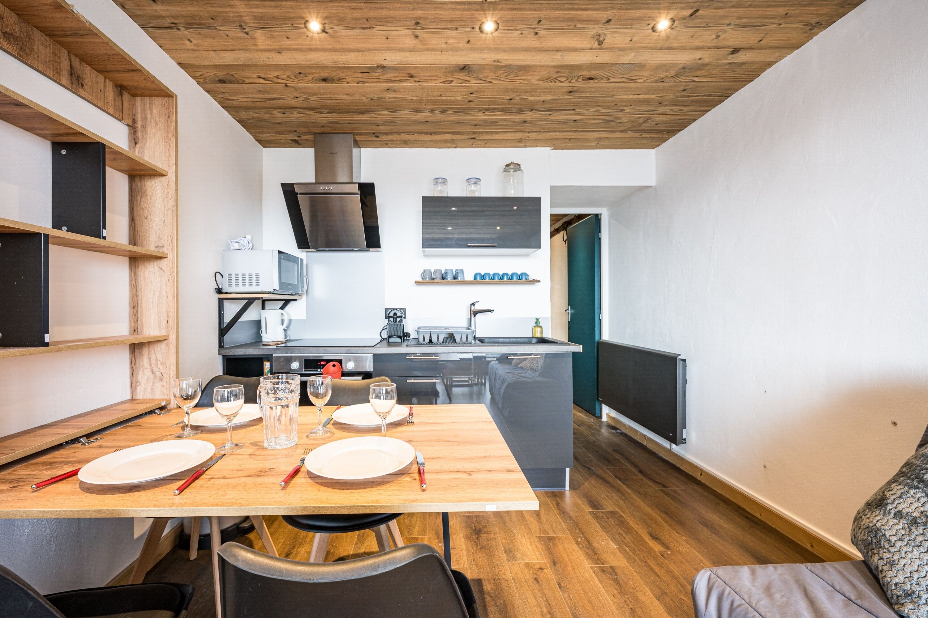 Una cocina moderna con techo de madera, estanterías empotradas y una isla central con pileta.