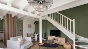 Una sala de estar moderna con una escalera, un comedor y un televisor.
