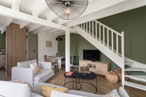 Ein modernes Wohnzimmer mit Treppe, Essbereich und Fernseher.
