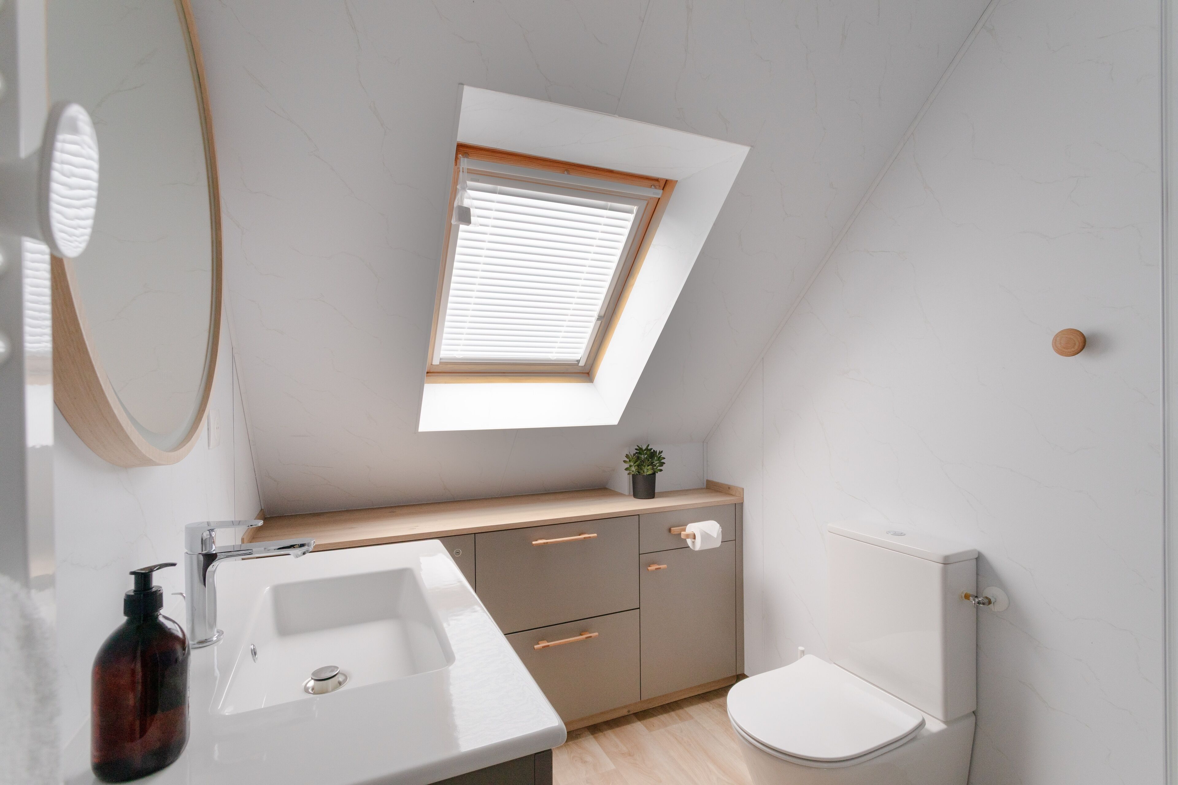 A modern bathroom with a skylight, a sink, a toilet, and a cabinet.
