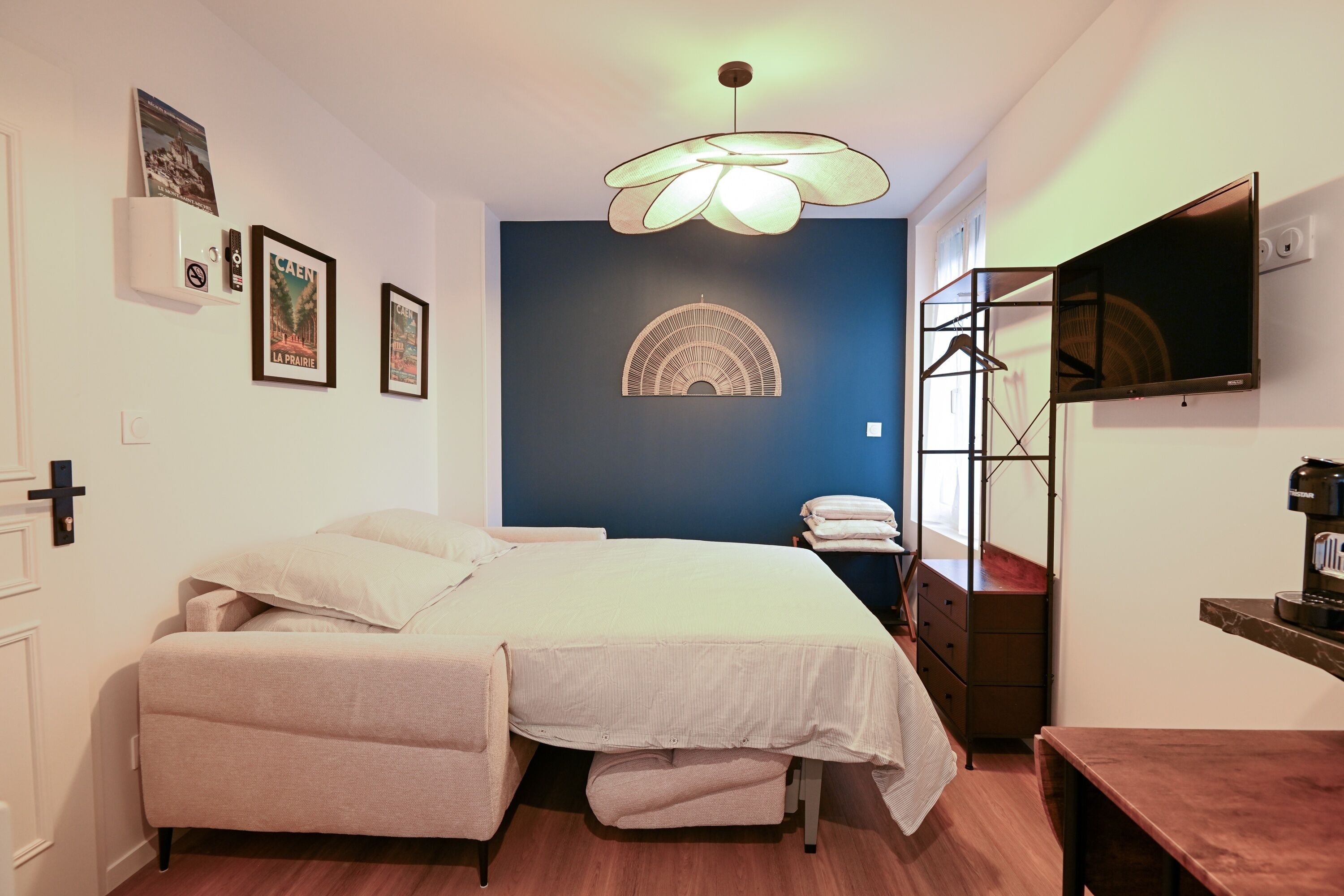 Una camera da letto con un letto, una cassettiera, una TV e una mensola a parete.