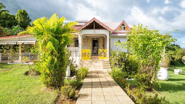 A house with a tiled pathway leading to the entrance, surrounded by lush greenery and a clear sky. - Soley Lodge - Climatisée avec terrasse et jardin (Plessis Nogent)