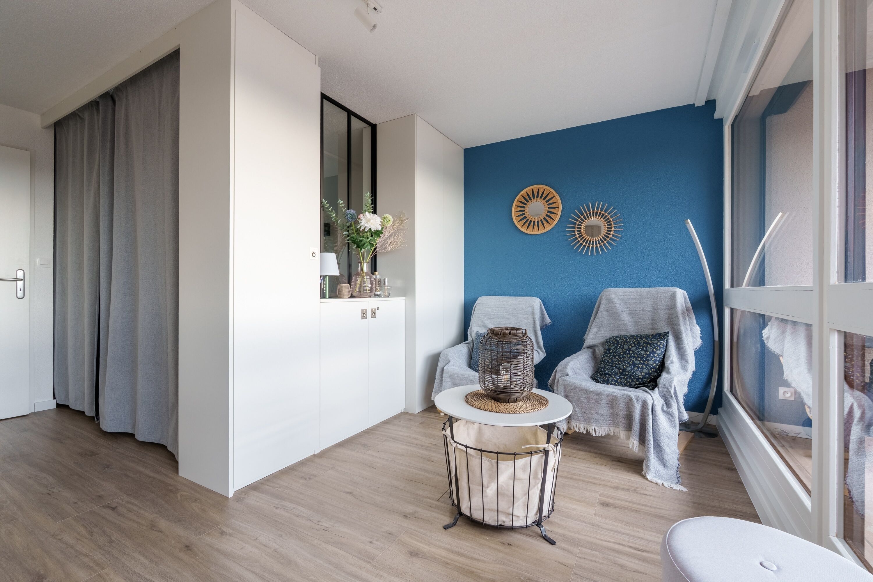 A modern living room with a blue accent wall, a round coffee table, and two armchairs.