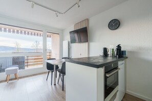 Ett modernt kök med en stor köksö, en matplats med stolar, ett kylskåp, en mikrovågsugn och en klocka på väggen.