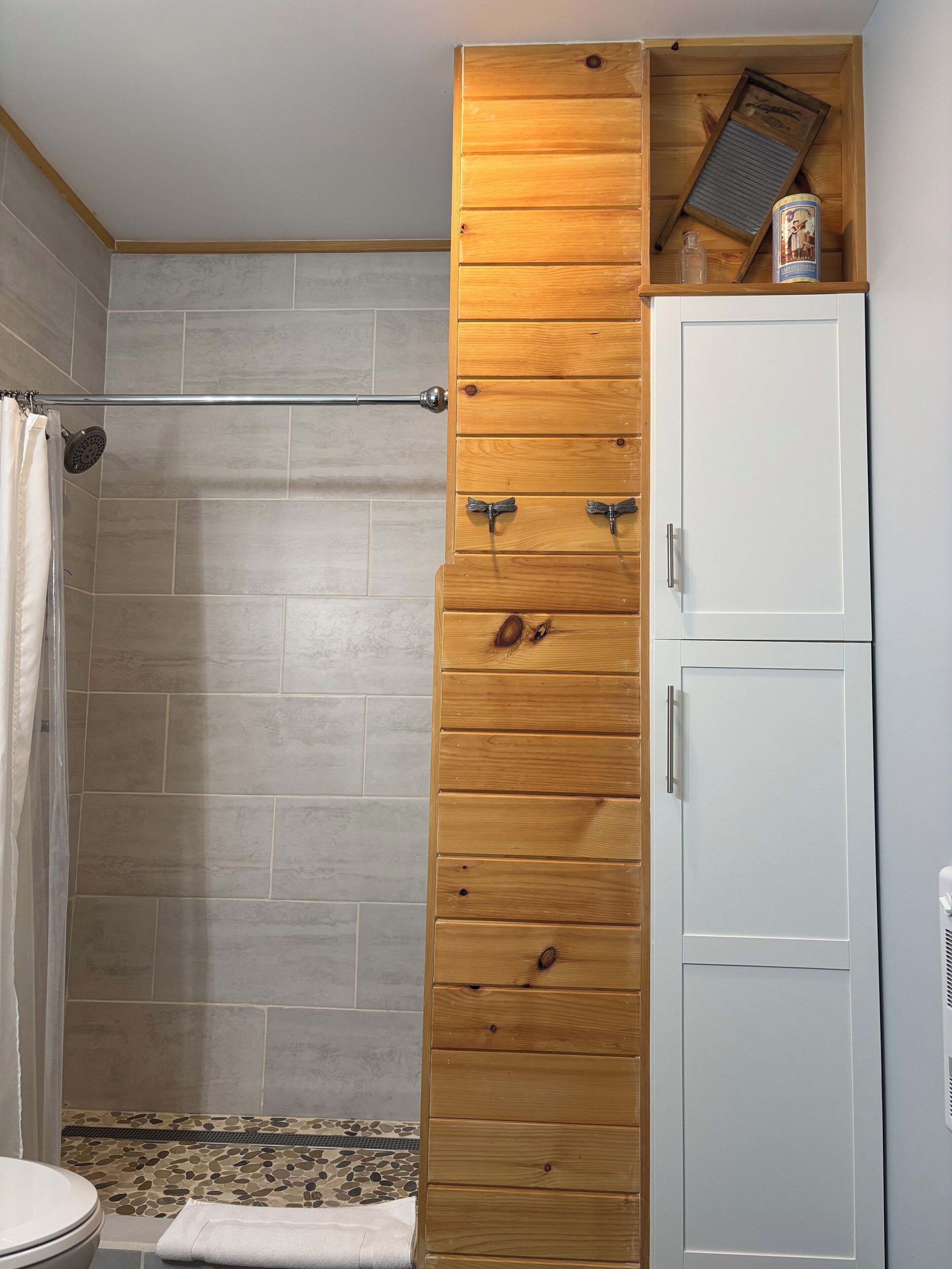 Un baño con ducha, un armario de madera y un inodoro.