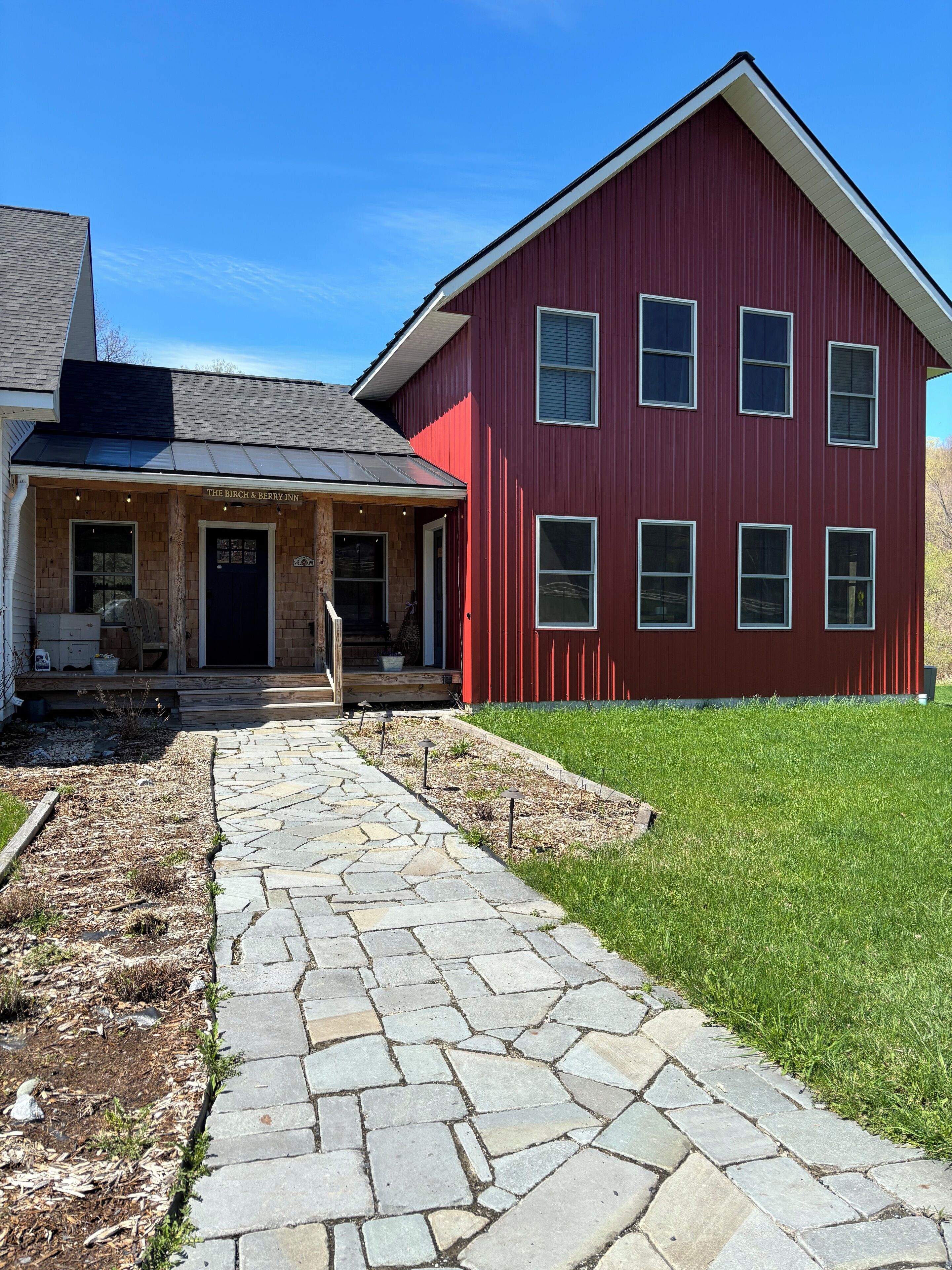 A red building with a stone pathway leading to a wooden porch.