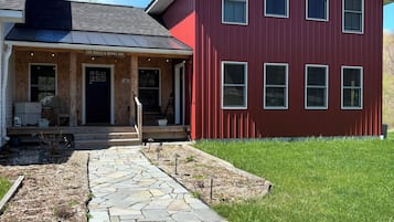 A red building with a stone pathway leading to a wooden porch.