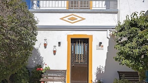 Un edificio con una puerta marrón, un banco y plantas en macetas.