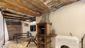 Un área de lavandería con lavadora, un horno de ladrillo y una mesa con sillas.