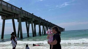 Una playa con un muelle al fondo.