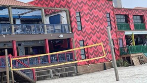 Un edificio con fachada de patrón rojo en zigzag, balcones con barandillas verdes y una red de seguridad amarilla.