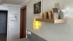 A modern bathroom with a wooden shelf holding decorative items, a neon sign, and a framed picture on the wall. - Double suite with sea view (Trieste)