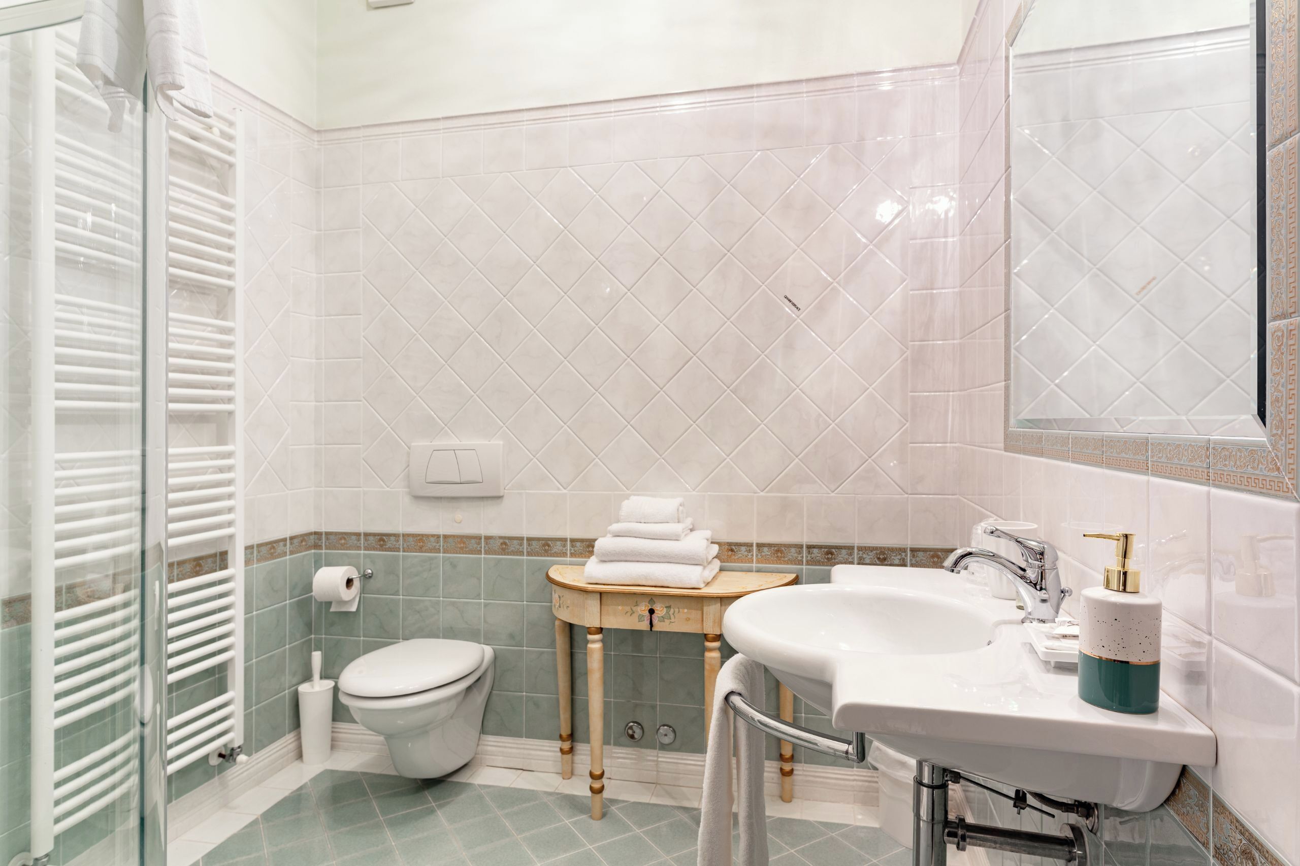 A bathroom with a toilet, sink, and glass shower enclosure.