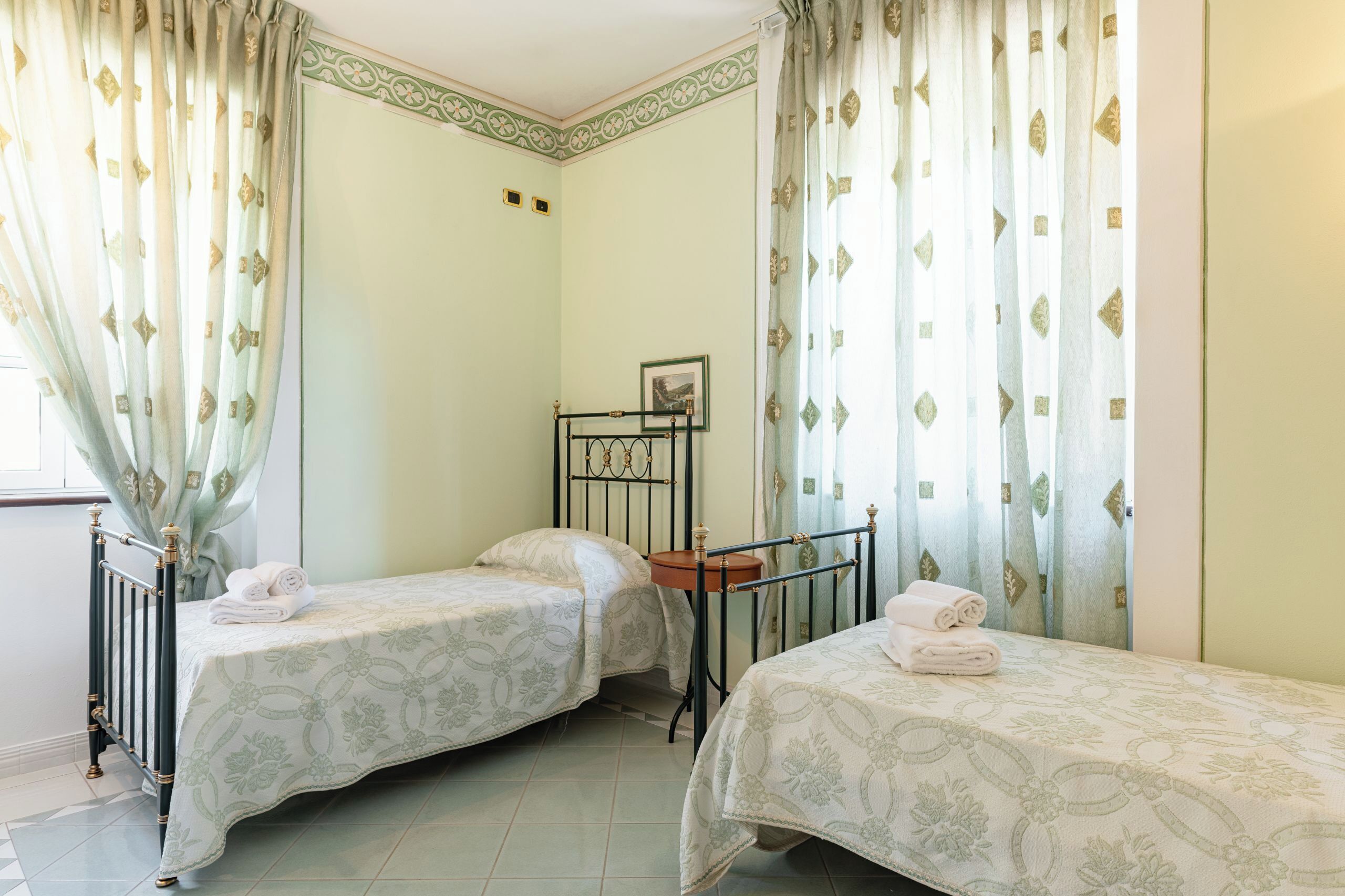 Ein Zimmer mit zwei Einzelbetten, einem kleinen Tisch und einem Stuhl.