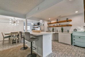 A modern kitchen with a central island, bar stools, pendant lights, and open shelving. - ♥Lady Victory♥Walk to Beach & Pleasure Pier/BBQPit (Galveston)