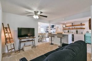 A modern living room with a TV, dark sofa, and a ceiling fan. - ♥Lady Victory♥Walk to Beach & Pleasure Pier/BBQPit (Galveston)
