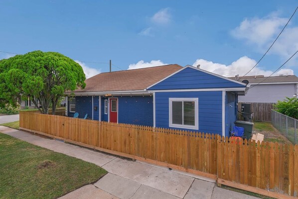 A single-story house with a blue exterior, a red door, and a wooden picket fence. - ♥Lady Victory♥Walk to Beach & Pleasure Pier/BBQPit (Galveston)
