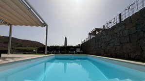 Une piscine avec un mur en pierre et un espace abrité.