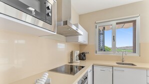 Une cuisine moderne équipée d’un four encastré, d’un lave-vaisselle et d’une fenêtre donnant sur l’extérieur.