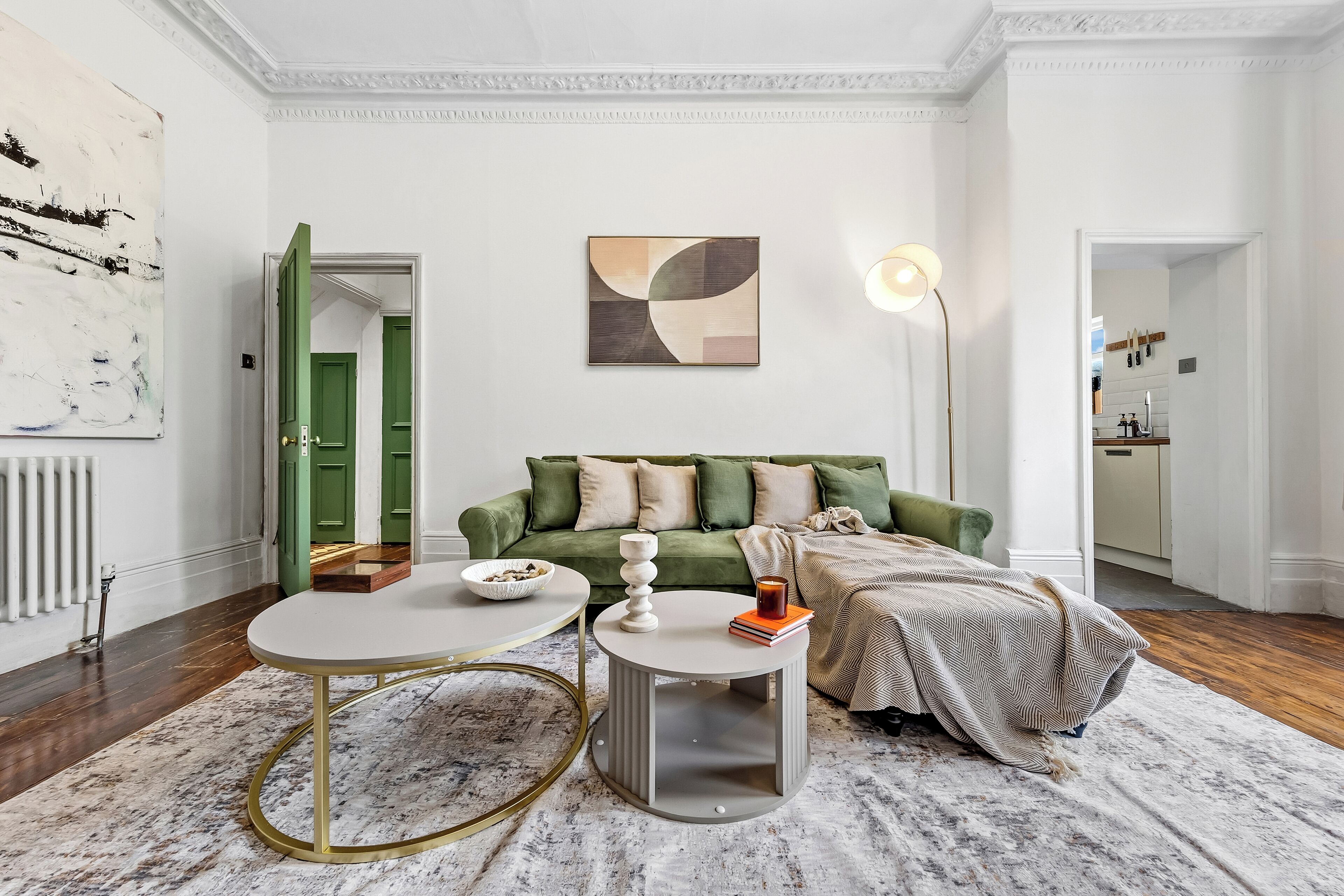 Un salon moderne avec un canapé vert, une table basse ronde et un lampadaire.