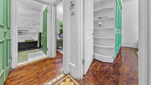 Un couloir avec un plancher en bois, des portes vertes et des murs blancs.