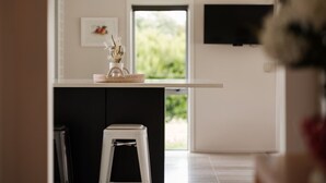 A modern kitchen with a white countertop, a small stool, and a basket with dried plants. - ⭐️ The Wine Country Retreat by Homello ⭐️ | Pool • Wineries • Wedding Venues (Kumeū)