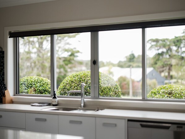 A kitchen with a large window, a sink, and a dish rack.