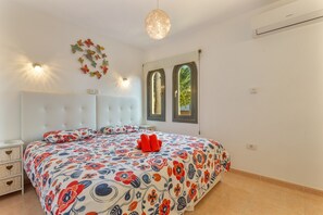 Une chambre à coucher comprenant un lit, des tables de chevet, un luminaire fixé au mur et une fenêtre donnant sur un paysage agréable.