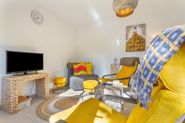 Un salon moderne avec un téléviseur à écran plat, un canapé, une table basse et un tapis à motifs.
