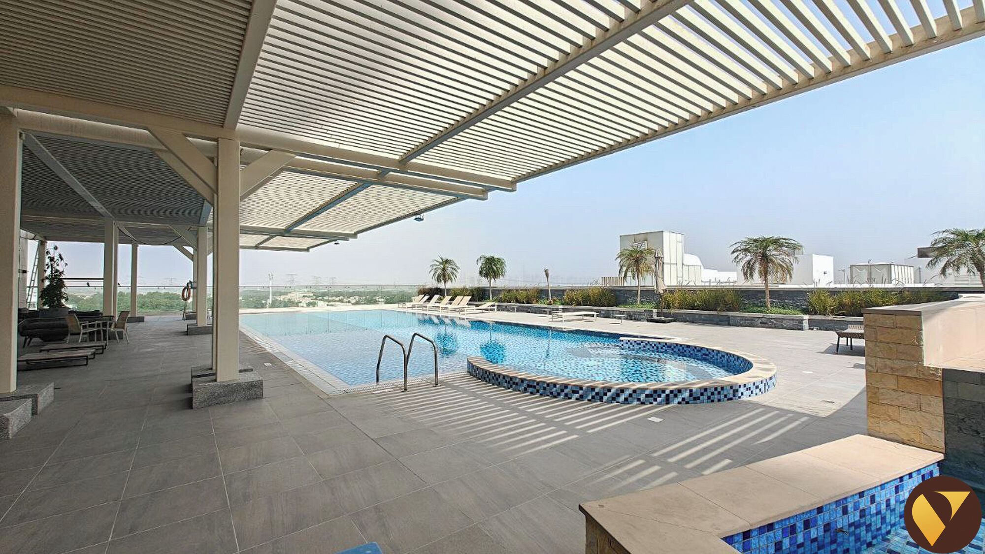 Une piscine sur le toit, dotée d’un espace salon couvert, de palmiers et offrant une vue dégagée sur le panorama urbain.