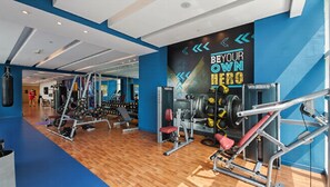 Une salle de sport équipée de divers appareils d  ’exercice, d’un sac de frappe et d’un mur décoré de citations motivantes.